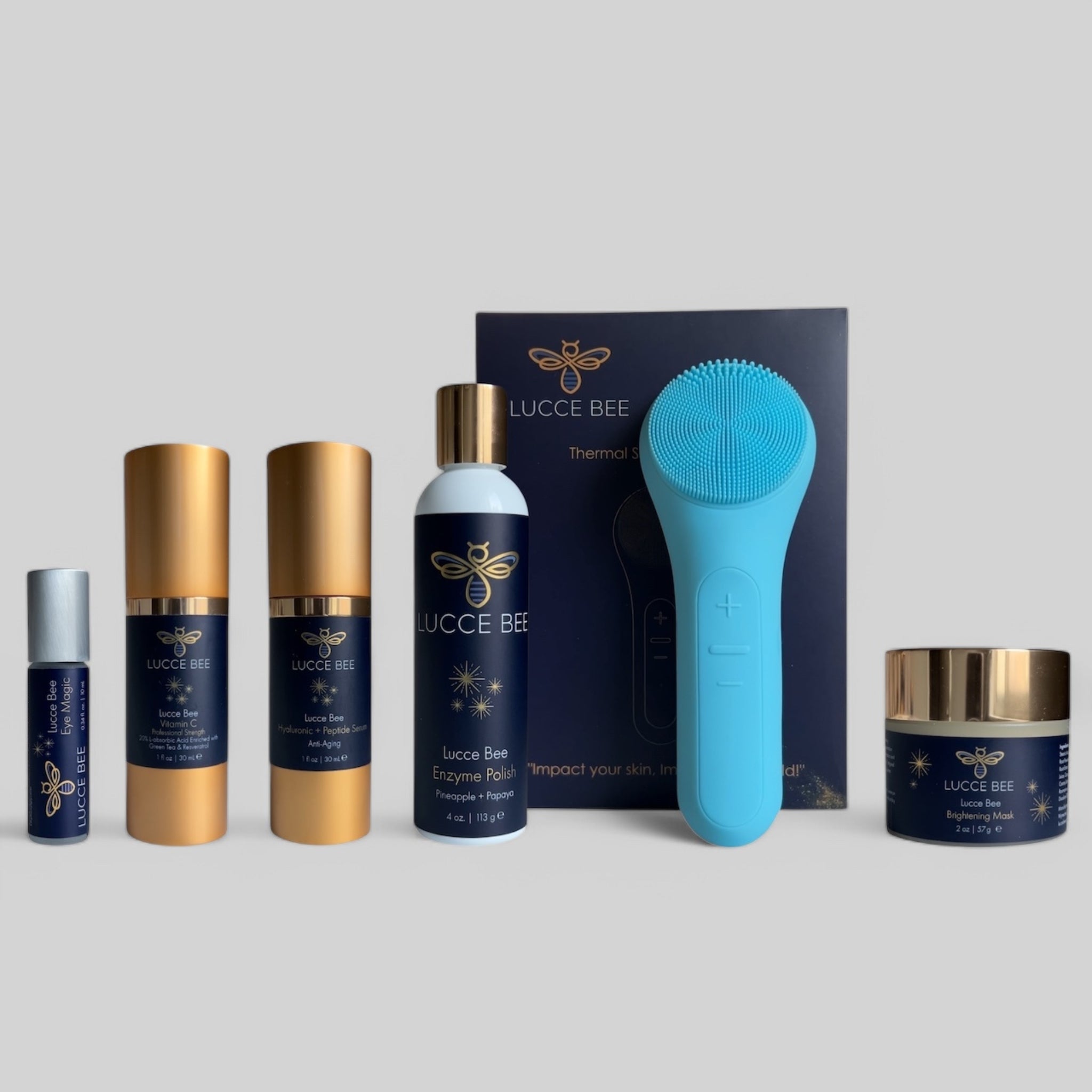 Lucce Bee skincare essentials bundle featuring Eye Magic, Vitamin C Serum, Hyaluronic + Peptide Serum, Enzyme Polish, Brightening Mask, and blue Thermal Sonic Facial Brush for glowing, healthy skin