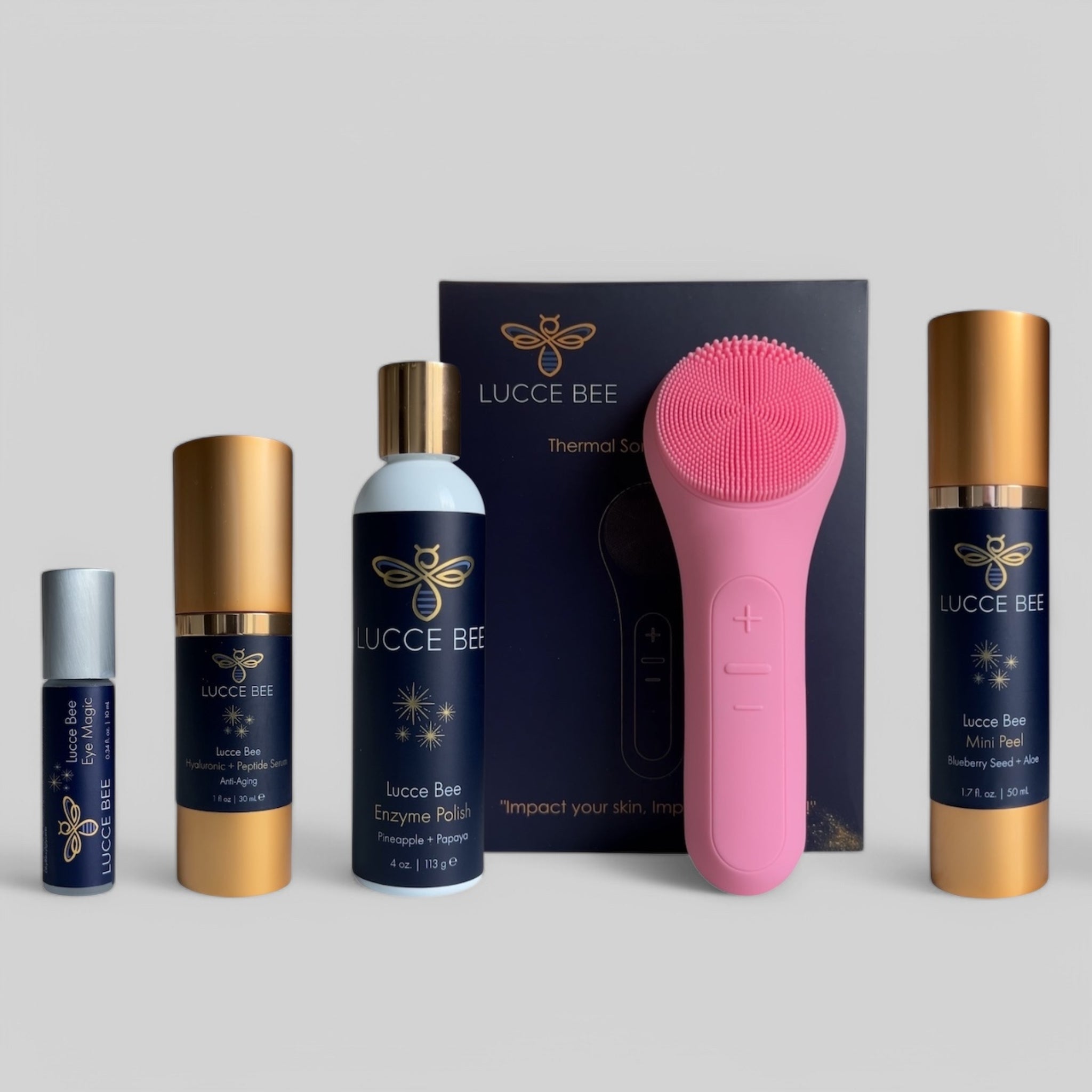 Lucce Bee complete skincare set featuring Eye Magic roller, Hyaluronic + Peptide Serum, Enzyme Polish, Mini Peel, and pink Thermal Sonic Facial Brush for luxury facial care and glowing skin