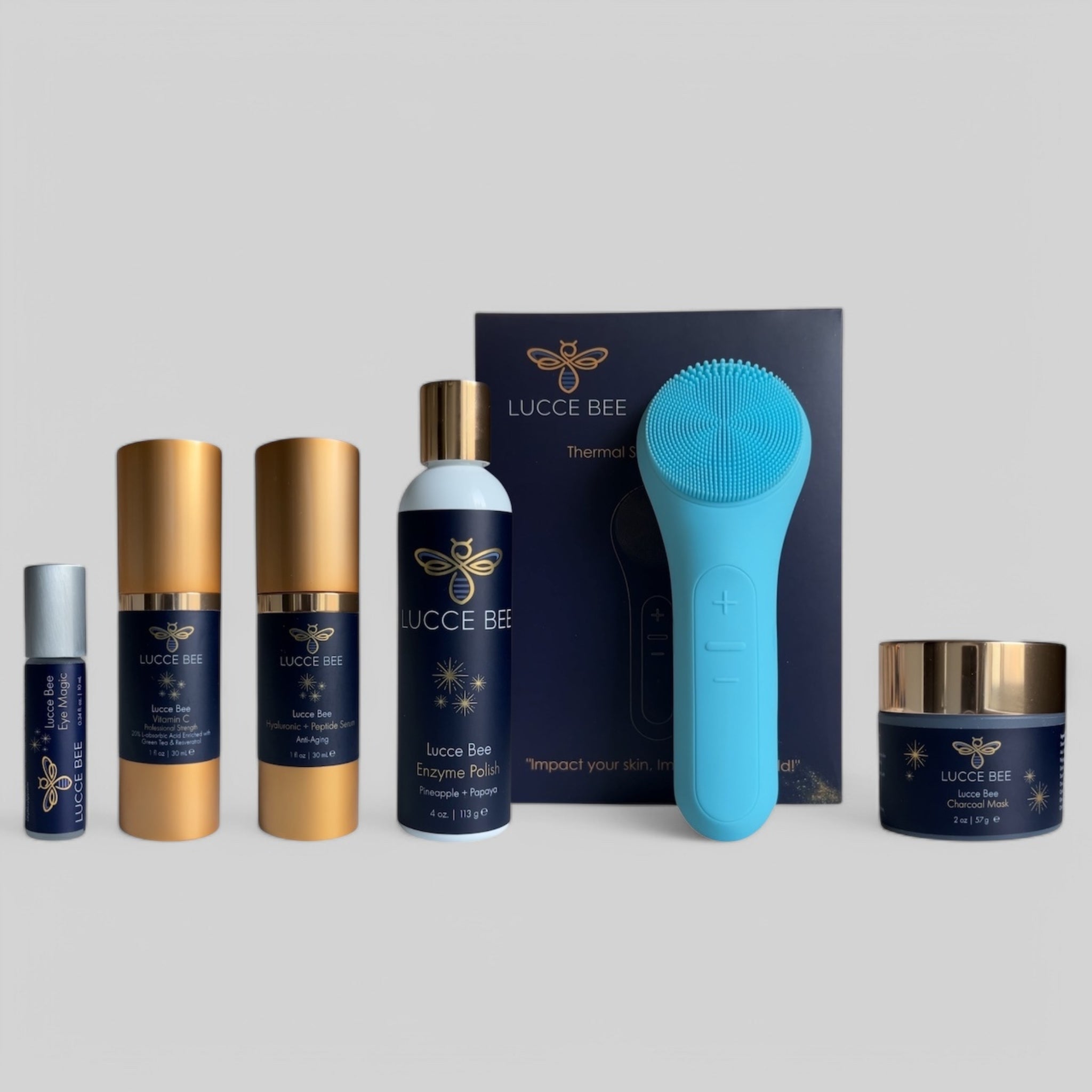 Lucce Bee skincare set featuring Eye Magic roller, Vitamin C serum, Hyaluronic + Peptide serum, Enzyme Polish, Charcoal Mask, and blue Thermal Sonic Facial Brush for deep cleansing and rejuvenated skin