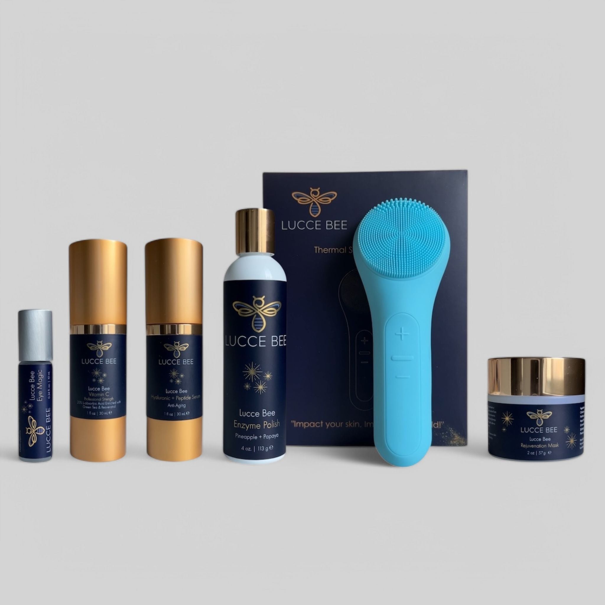 Lucce Bee skincare essentials set featuring Eye Magic, Vitamin C serum, Hyaluronic + Peptide serum, Enzyme Polish, Rejuvenation Mask, and blue Thermal Sonic Facial Brush — luxury skincare set for glowing, healthy skin
