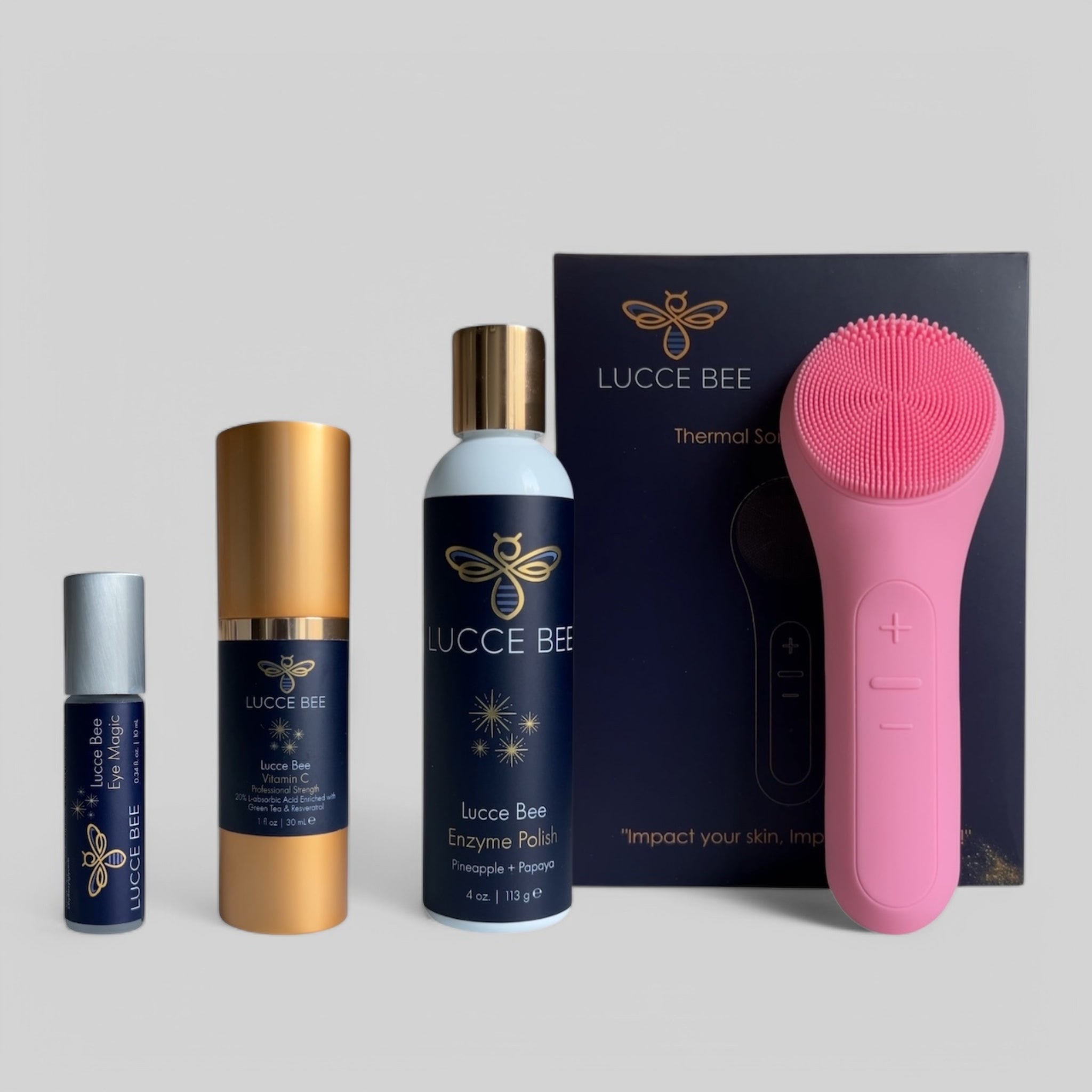 Lucce Bee skincare set with Eye Magic roller, Vitamin C Serum, Enzyme Polish with Pineapple + Papaya, and pink Thermal Sonic Facial Brush for radiant, youthful skin