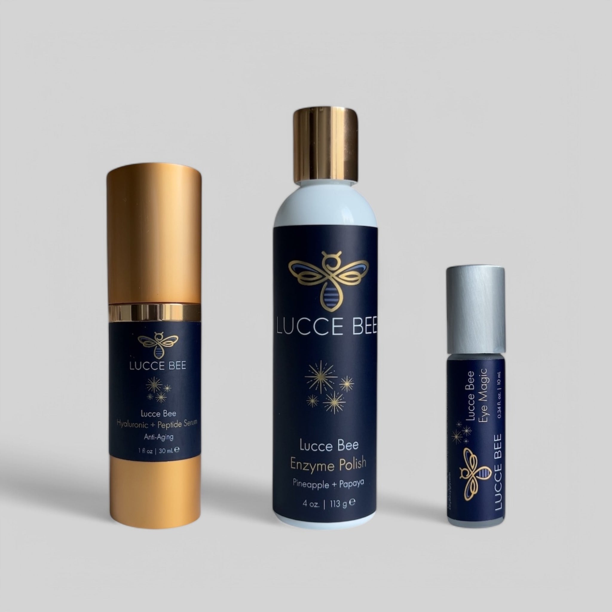 Lucce Bee Skincare Set – Hyaluronic + Peptide Serum, Enzyme Polish with Pineapple + Papaya, and Eye Magic Roller in elegant gold and navy packaging