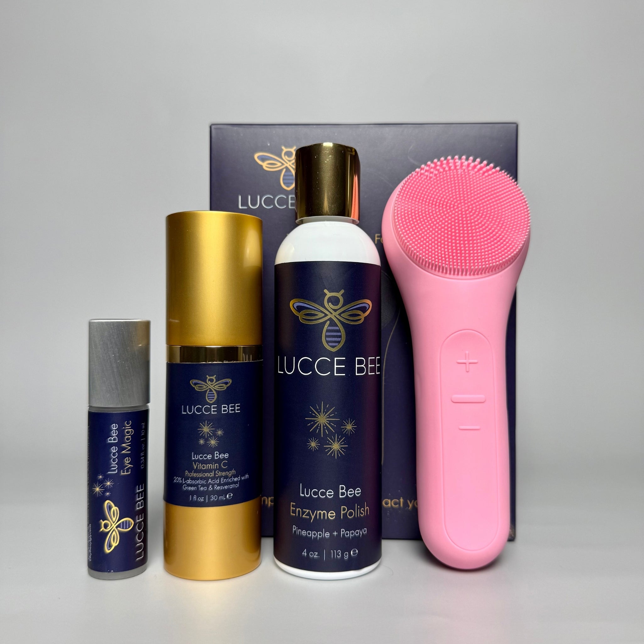 Lucce Bee skincare set featuring Eye Magic, Vitamin C Serum, Enzyme Polish, and pink silicone cleansing brush. Curated facial care essentials for anti-aging, exfoliation, hydration, and spa-like at-home skincare routines. Reveal radiant, healthy skin.